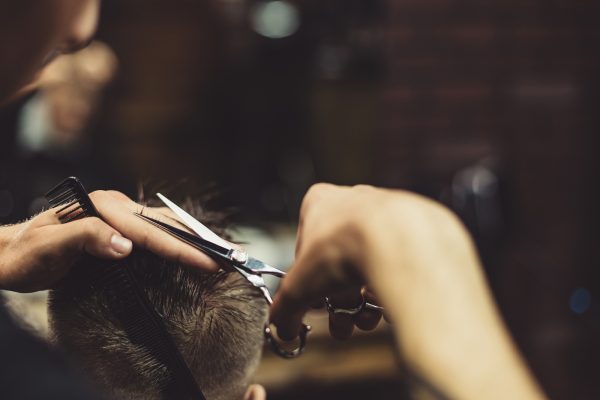 Crop barber doing haircut for client